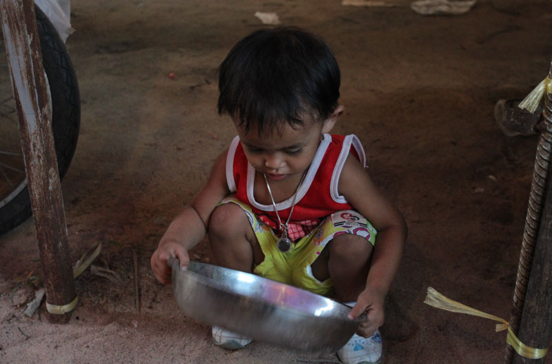 Small Thai boy playing with steel pan at local market
